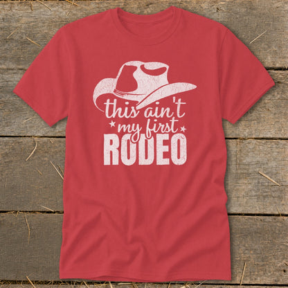 Red t-shirt with white text and cowboy hat graphic that reads "this ain't my first RODEO".