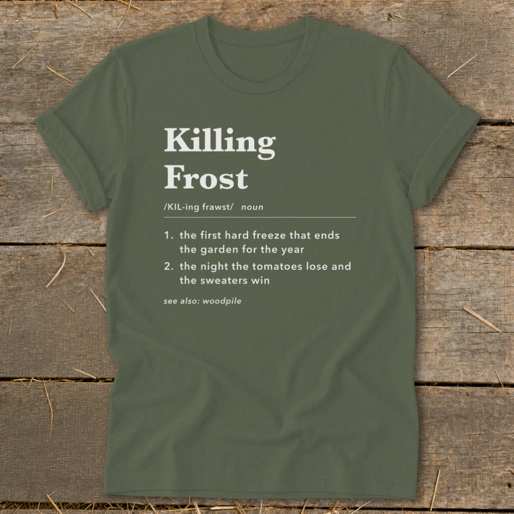 An olive green t-shirt featuring dictionary-style text defining Killing Frost on a wooden background.