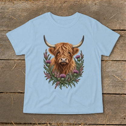 Highland cow portrait surrounded by thistles on a light blue t-shirt.