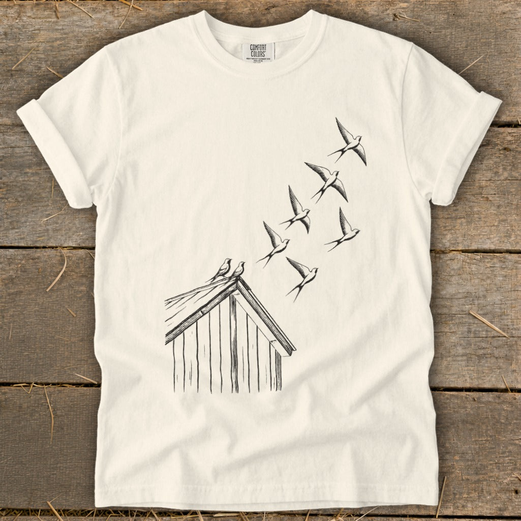 Off-white crewneck t-shirt featuring a black line drawing of birds flying from a small wooden house.