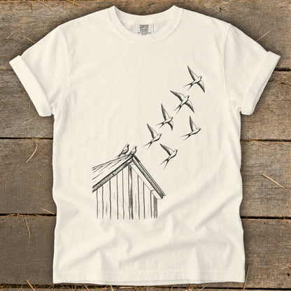 Off-white crewneck t-shirt featuring a black line drawing of birds flying from a small wooden house.