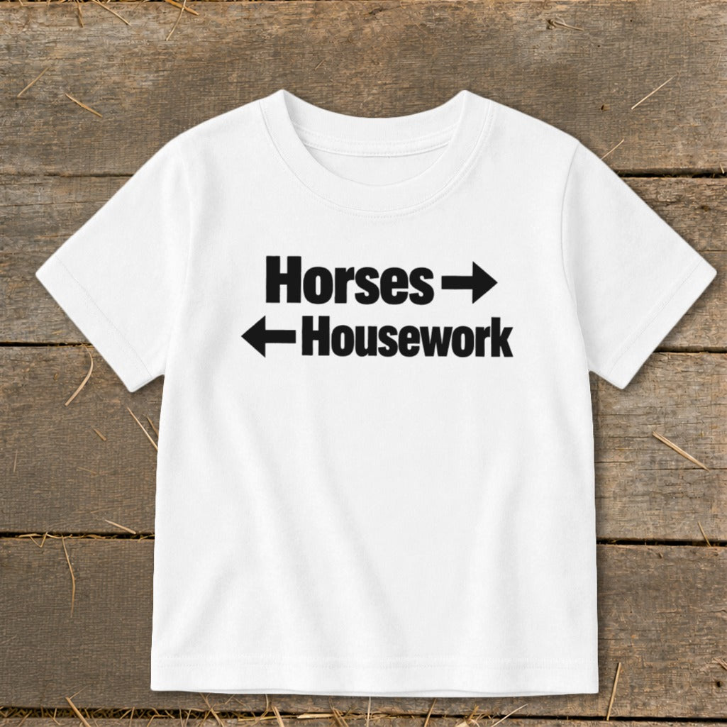 White short-sleeved t-shirt with black text that reads "Horses" with a right arrow and "Housework" with a left arrow.