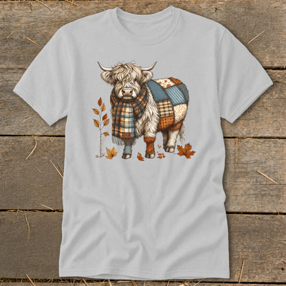 Highland cow with plaid scarf and patchwork body surrounded by autumn leaves.