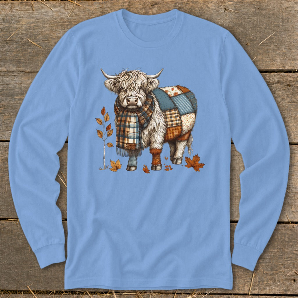 Highland cow with patchwork coat and plaid scarf surrounded by autumn leaves.