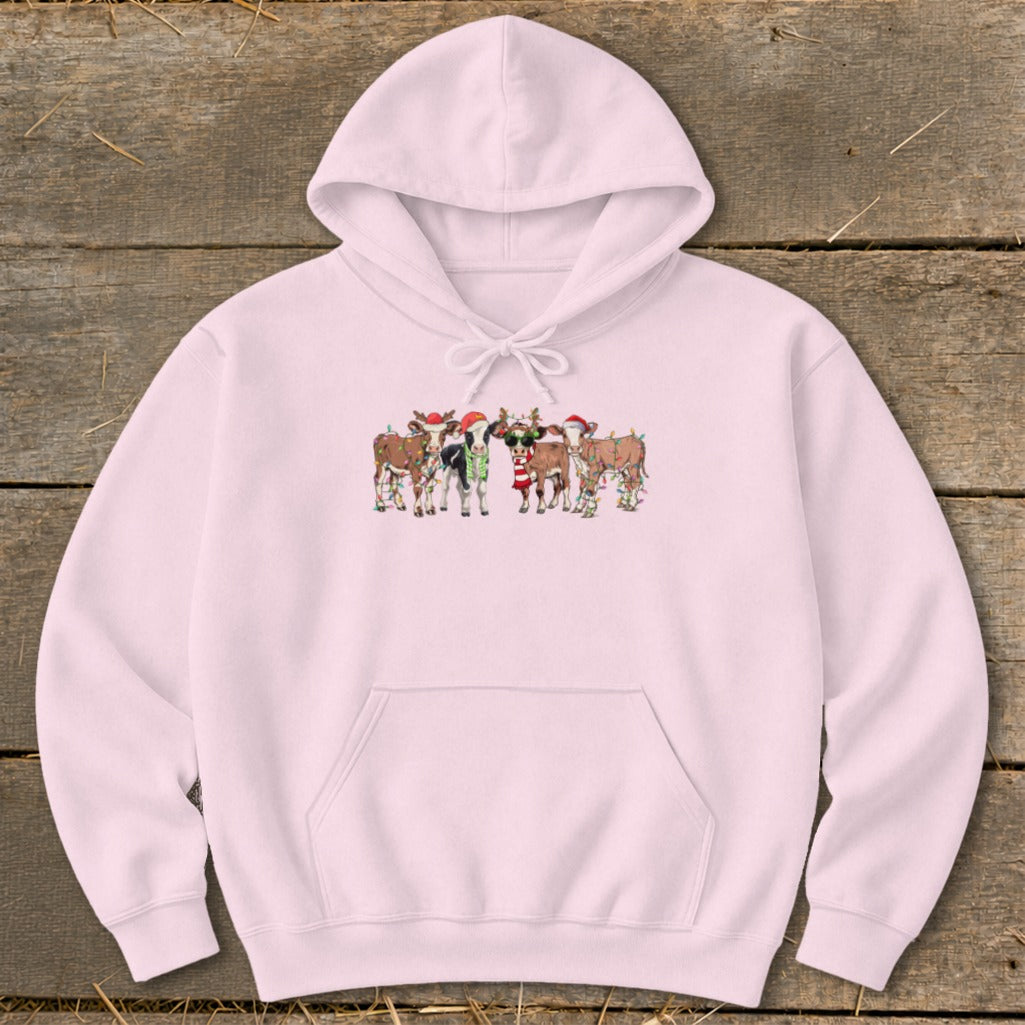 Pink hoodie with a group of cartoon cows wearing Christmas hats and lights.