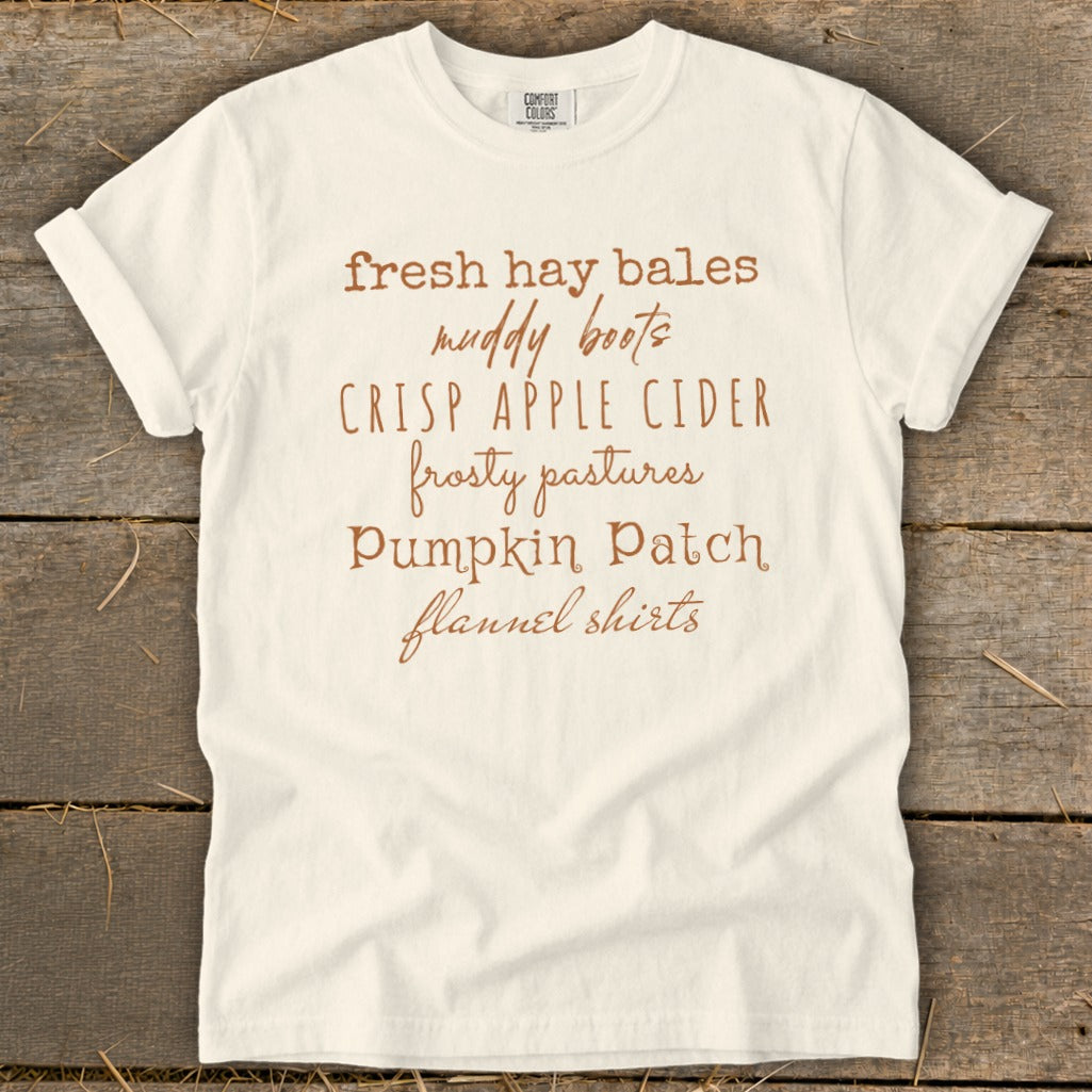 White t-shirt with "fresh hay bales, muddy boots, crisp apple cider, frosty pastures, pumpkin patch, flannel shirts" text.