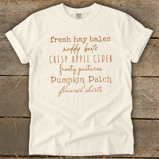 White t-shirt with "fresh hay bales, muddy boots, crisp apple cider, frosty pastures, pumpkin patch, flannel shirts" text.