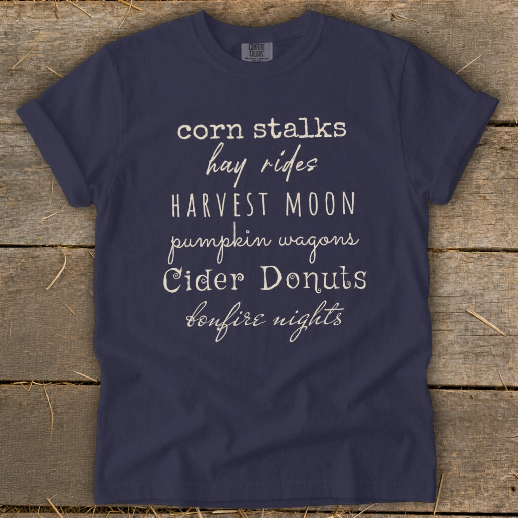 Navy t-shirt with white text listing fall activities like corn stalks and cider donuts.