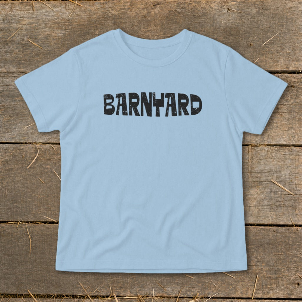 Light blue short-sleeve t-shirt with distressed black text reading BARNYARD centered on the chest, laid flat on a wooden surface.