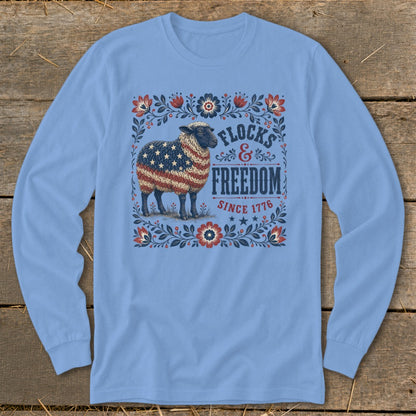 Sheep with American flag pattern on fleece shirt with "Flocks & Freedom Since 1776" text.