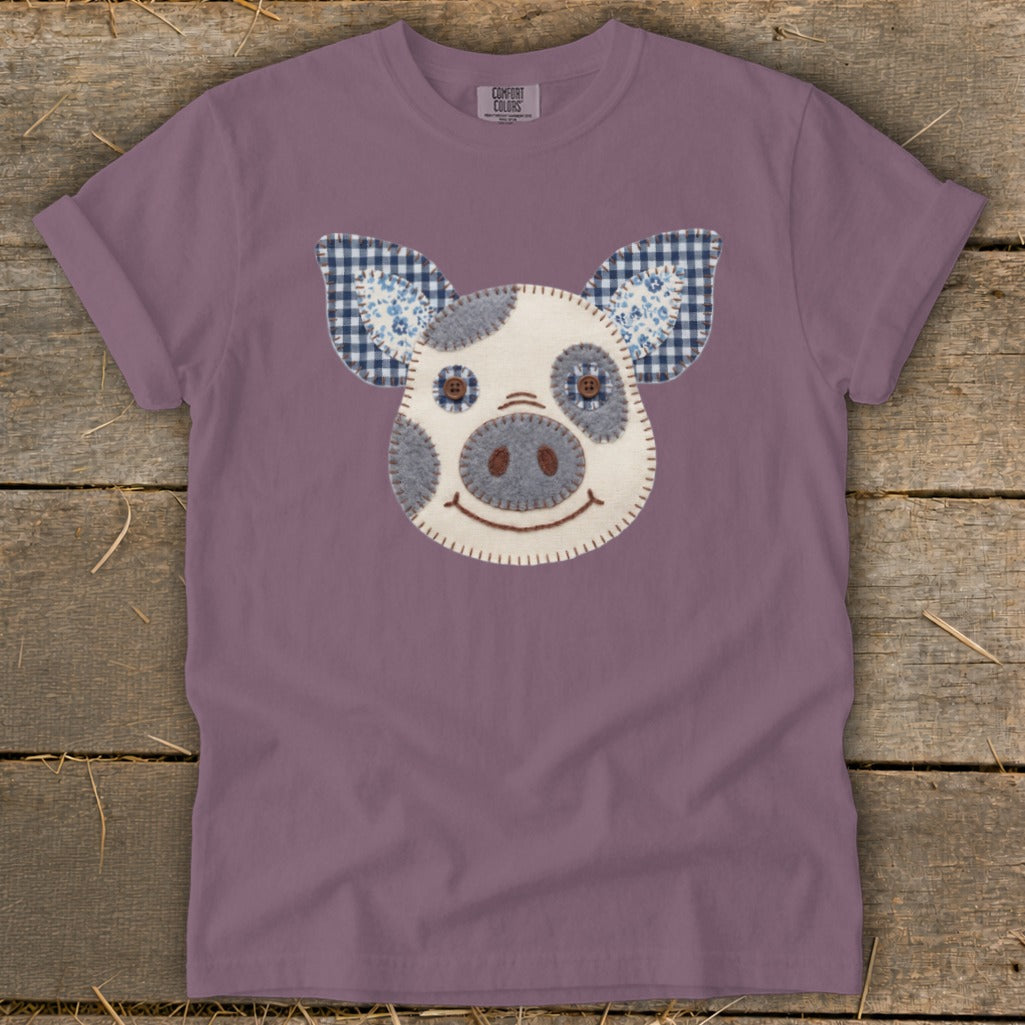 Purple t-shirt with a stitched appliqué of a pig's face and ears.