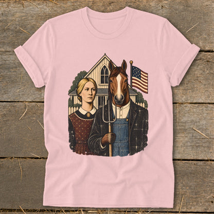 Light pink t-shirt featuring a satirical American Gothic parody graphic with a woman and a horse-headed farmer holding a pitchfork.