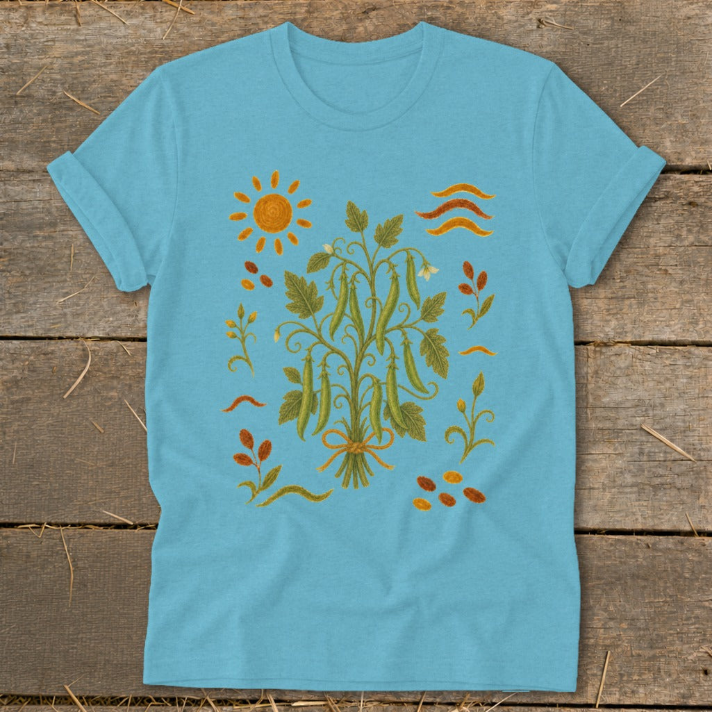 Light blue t-shirt with a detailed illustration of a pea plant with pods, sun, and leaves.