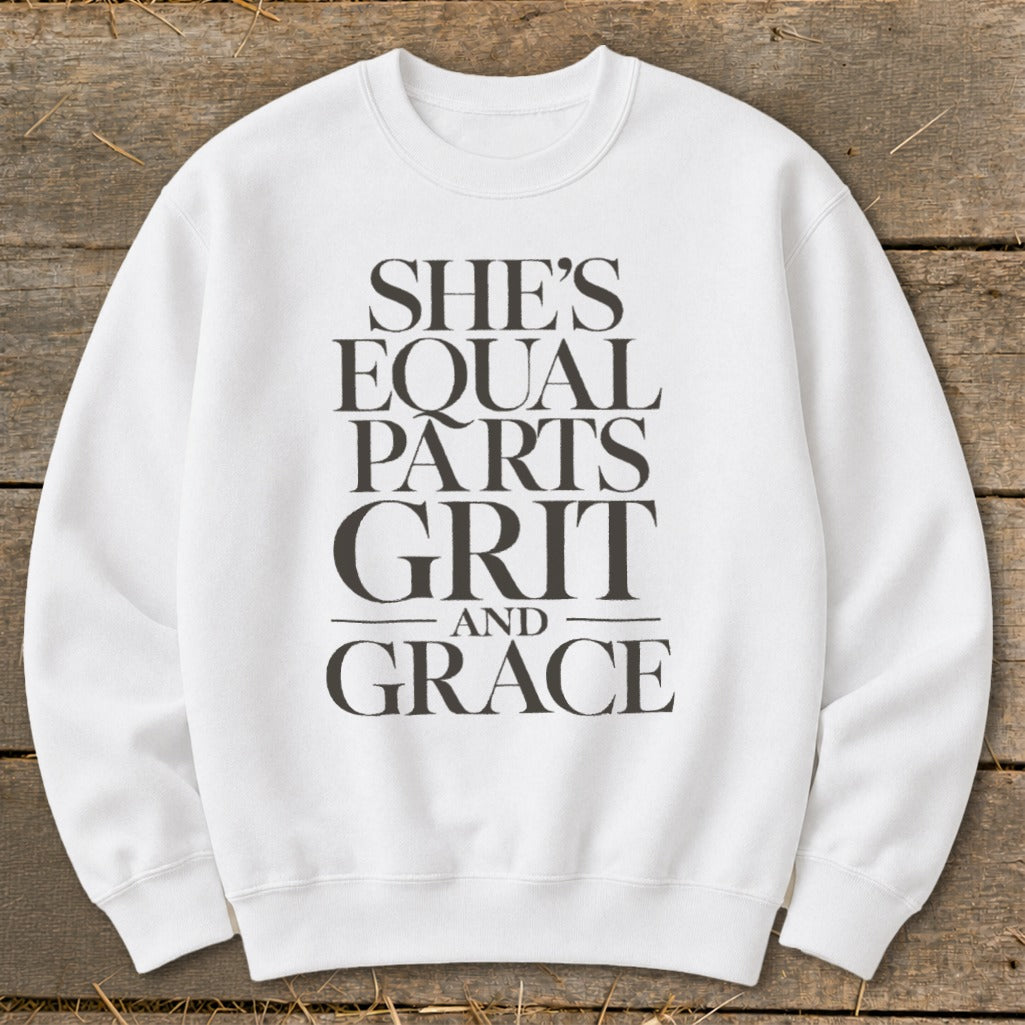 White sweatshirt with black text reading "SHE'S EQUAL PARTS GRIT AND GRACE."