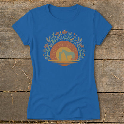 Blue t-shirt with a graphic of a girl, horse, sun, and floral wreath.