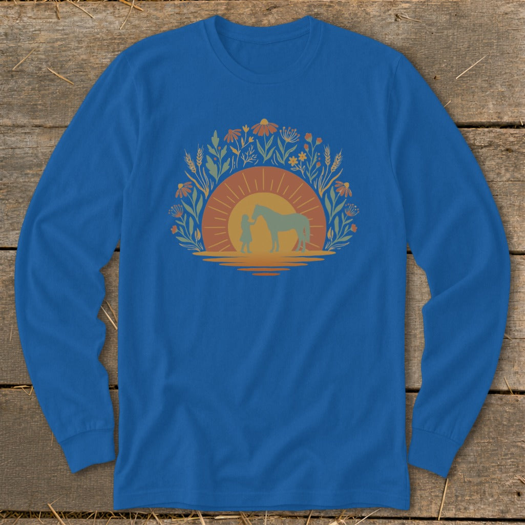 Blue long sleeve shirt with a graphic of a person and horse at sunset within a floral arch.