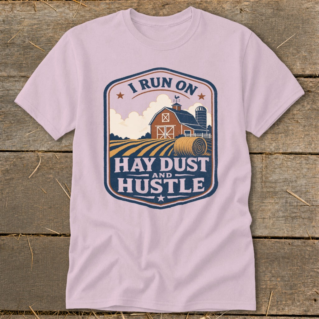 Pink t-shirt with a farm scene and "I Run On Hay Dust And Hustle" text.