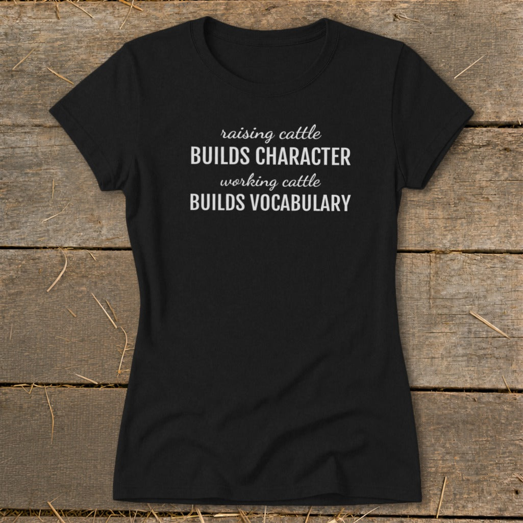 Black t-shirt with white text: "raising cattle BUILDS CHARACTER working cattle BUILDS VOCABULARY".