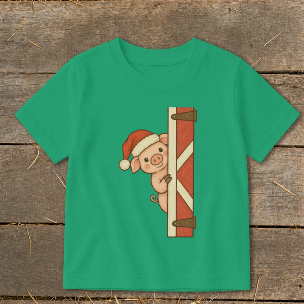 Green t-shirt with a Christmas pig peeking from behind a barn door graphic.