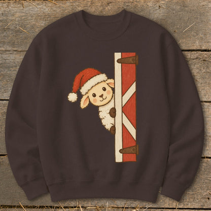 Sheep wearing Santa hat peeking from barn door on dark brown sweatshirt.