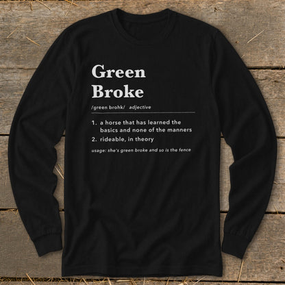 Black long-sleeve t-shirt with white text defining green broke on a rustic wooden background.