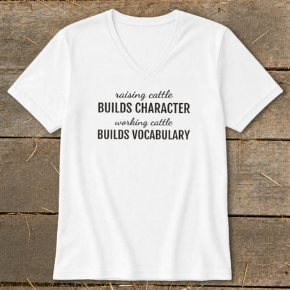 White v-neck t-shirt with black text: "raising cattle BUILDS CHARACTER, working cattle BUILDS VOCABULARY."