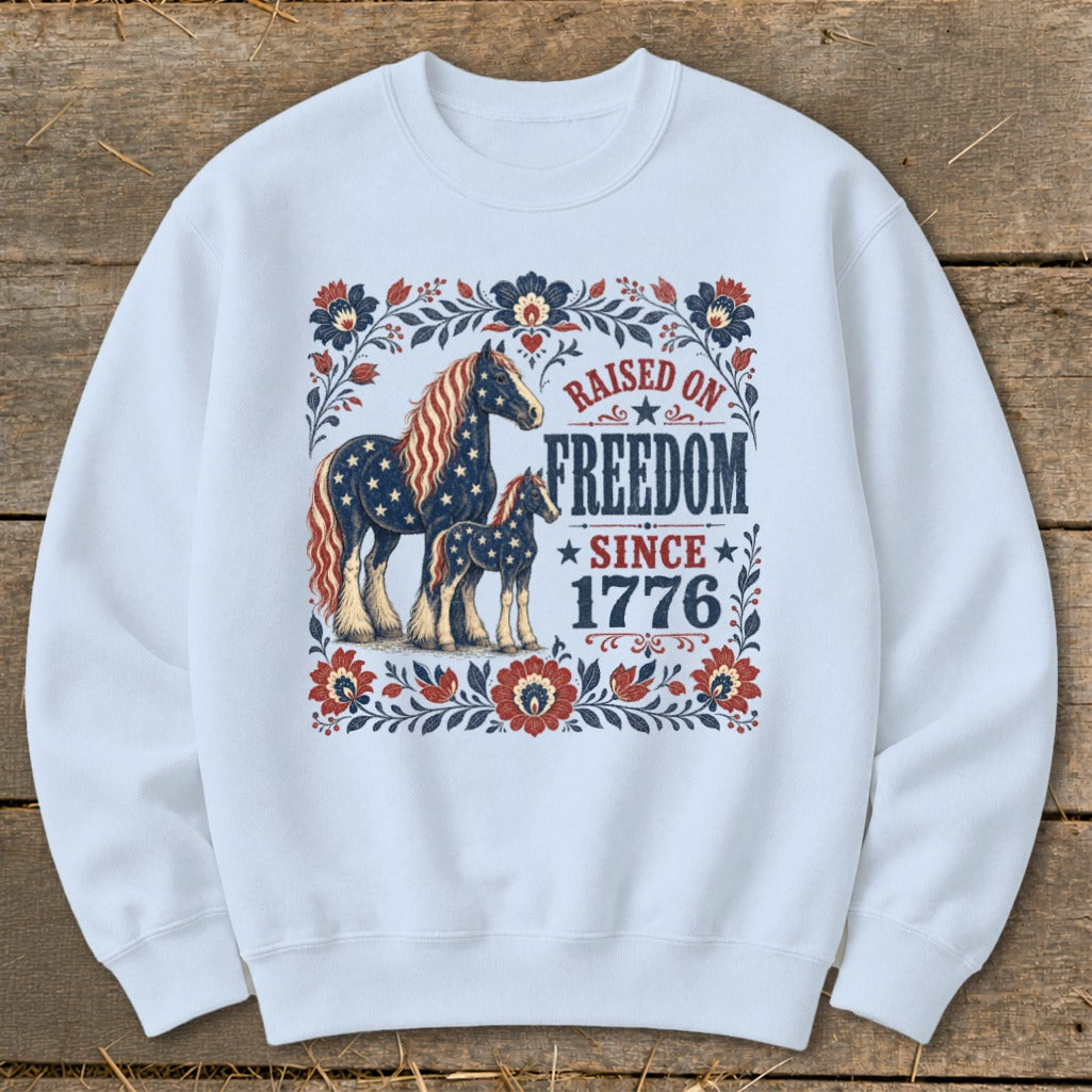 Light blue sweatshirt with patriotic horses and "Raised on Freedom Since 1776" text.