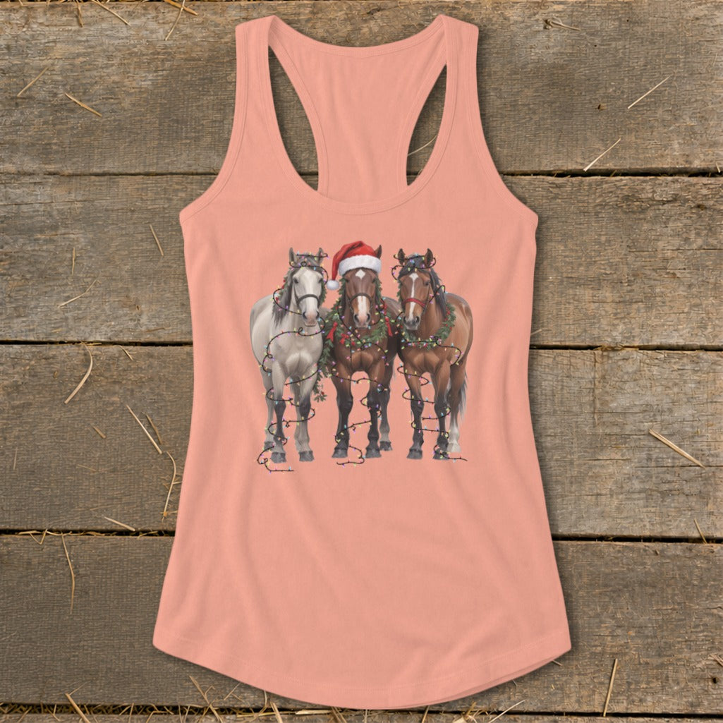 Three horses, two with festive Christmas lights, one wearing a Santa hat.