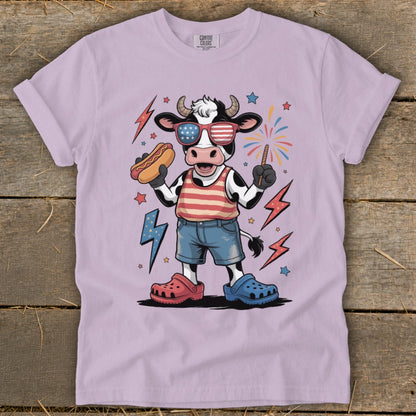Cow in patriotic attire holding hot dog, with fireworks and lightning bolts.