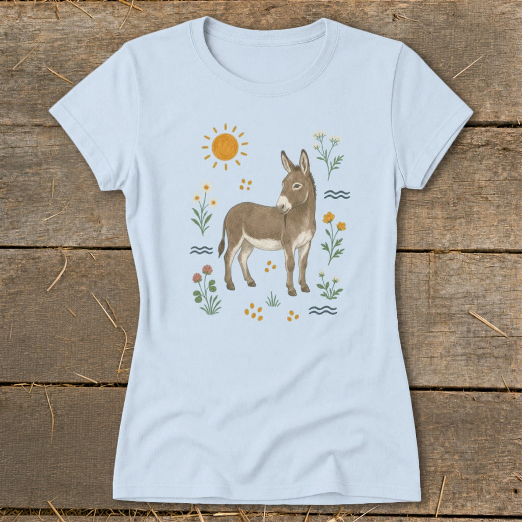 Light blue t-shirt with a watercolor illustration of a donkey, sun, flowers, and waves.