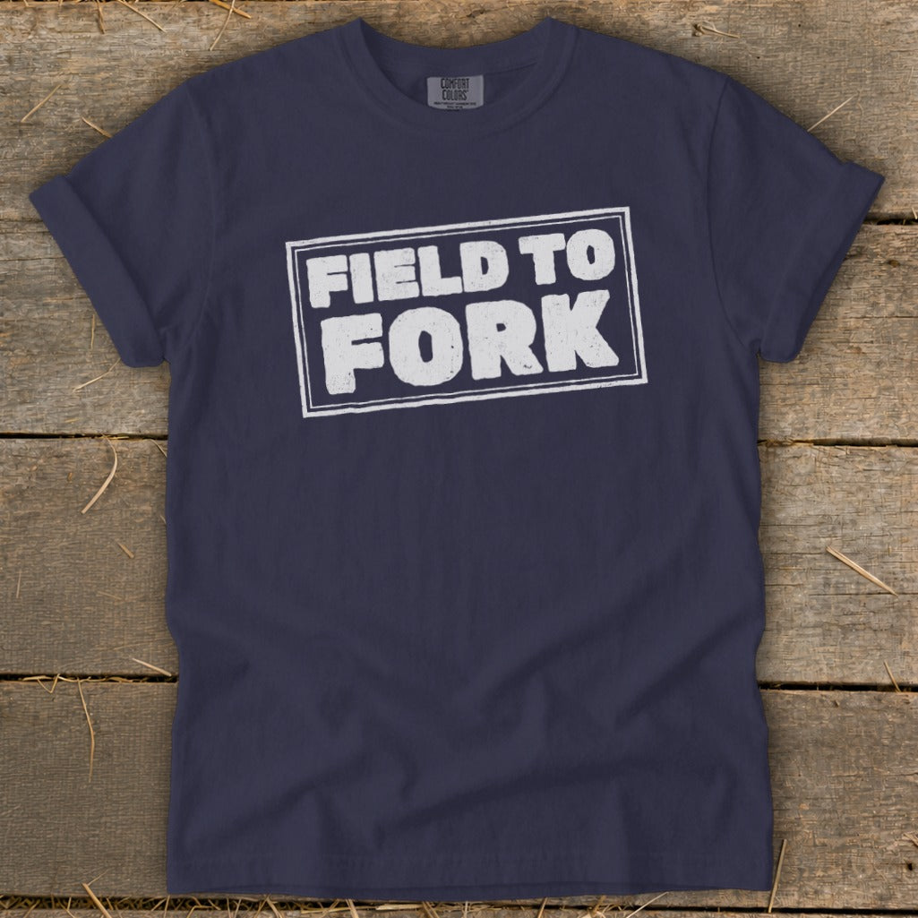Dark blue crewneck t-shirt with rolled sleeves displaying the white distressed text FIELD TO FORK.