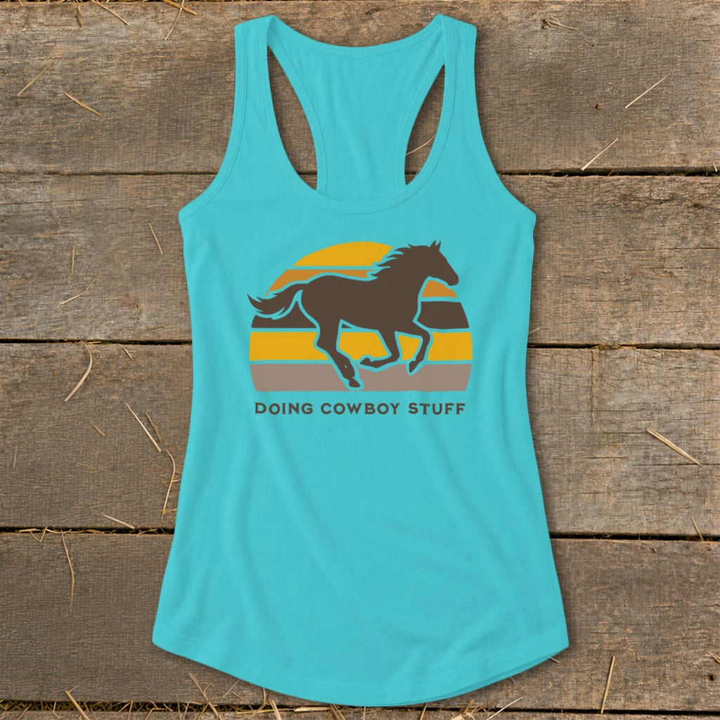 Turquoise tank top with running horse silhouette over striped sunset and text "DOING COWBOY STUFF".