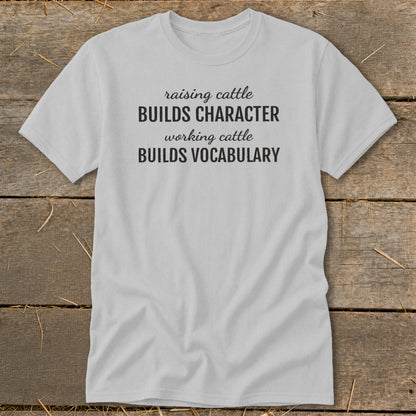 Light gray t-shirt with text "raising cattle BUILDS CHARACTER working cattle BUILDS VOCABULARY."