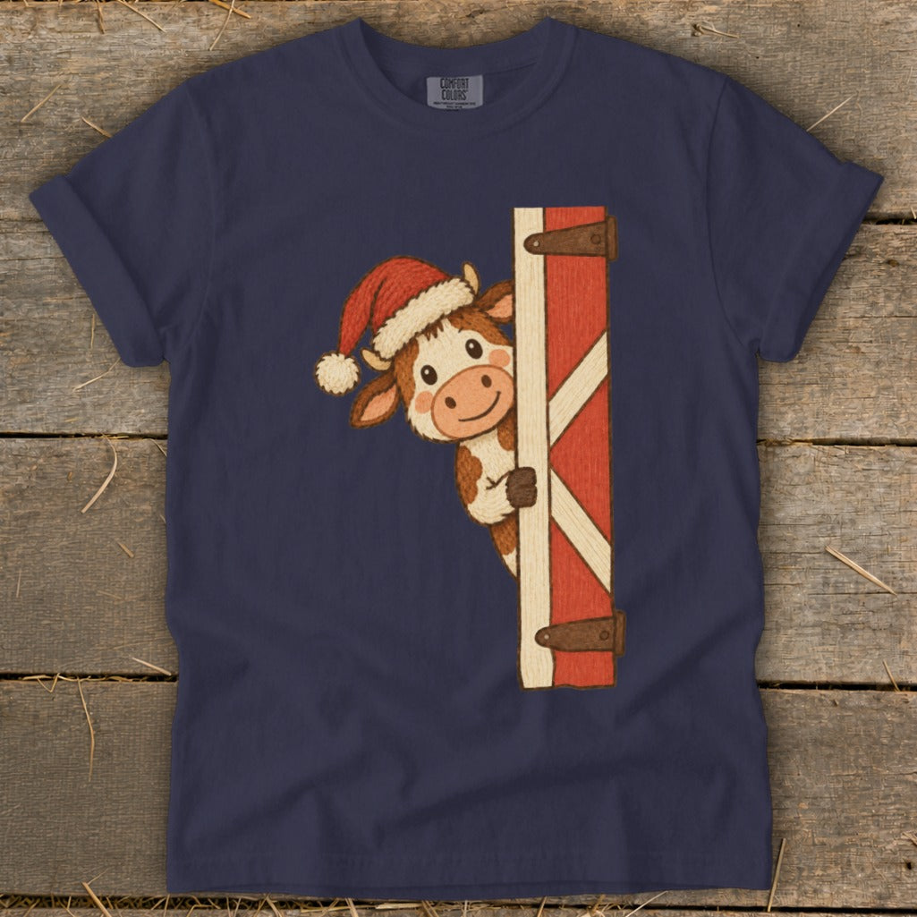 Navy t-shirt with a cartoon cow wearing a Santa hat peeking from behind a red barn door.