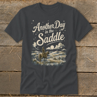 Dark grey t-shirt with "Another Day in the Saddle" graphic of a cowboy on horseback at dusk.