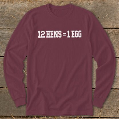 Maroon long-sleeve t-shirt with white text reading 12 HENS = 1 EGG laid flat on wood.