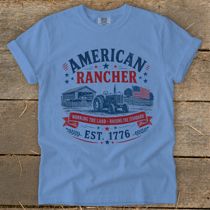 Light blue t-shirt with "AMERICAN RANCHER" design featuring barn, tractor, flag, and "EST. 1776".