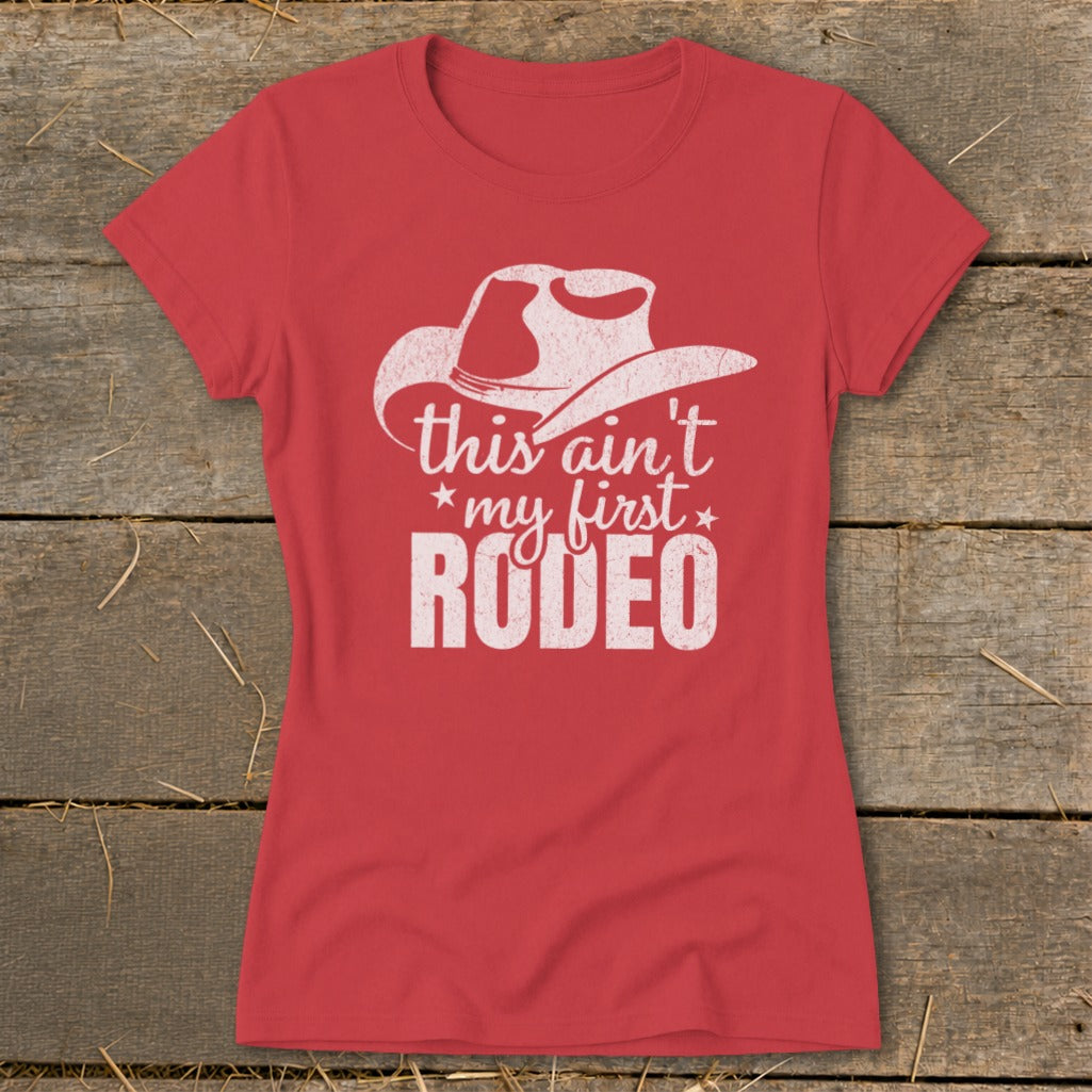 Red t-shirt with white text "this ain't my first RODEO" and a cowboy hat graphic.