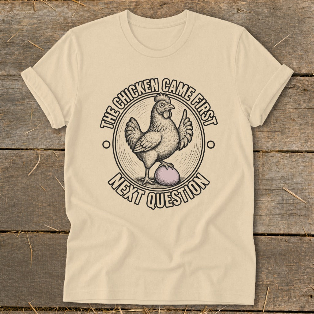 Cream t-shirt with graphic of chicken on egg, text "The chicken came first, next question."