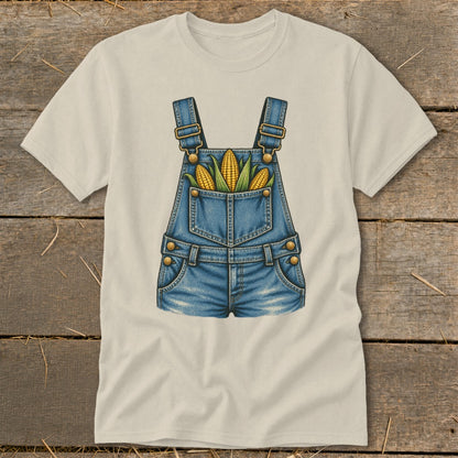 Cream t-shirt with graphic of denim overalls and three ears of corn in pocket.
