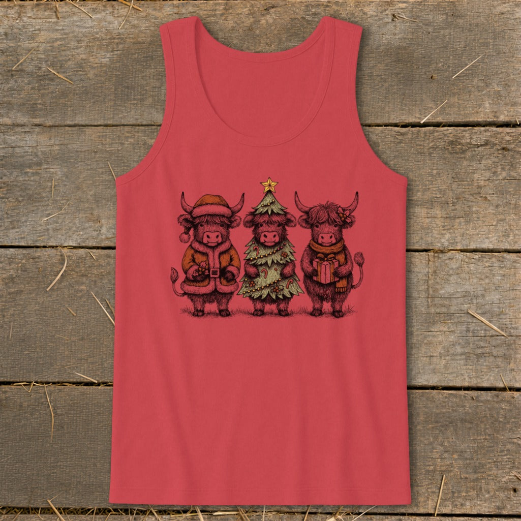 Three highland cows in Christmas attire, one as Santa, one as a tree, one holding a gift.