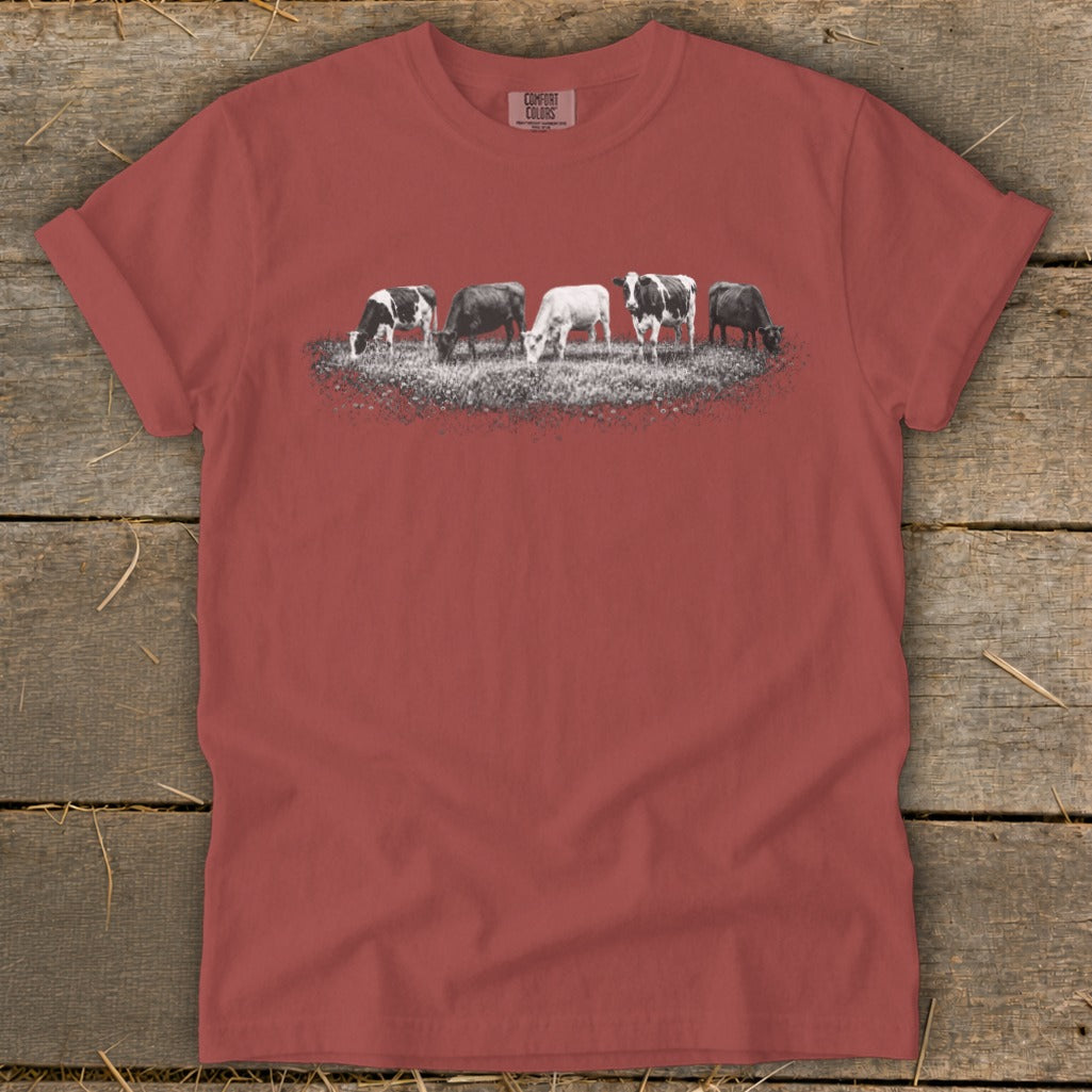 T-shirt with a graphic of five cows grazing in a field.