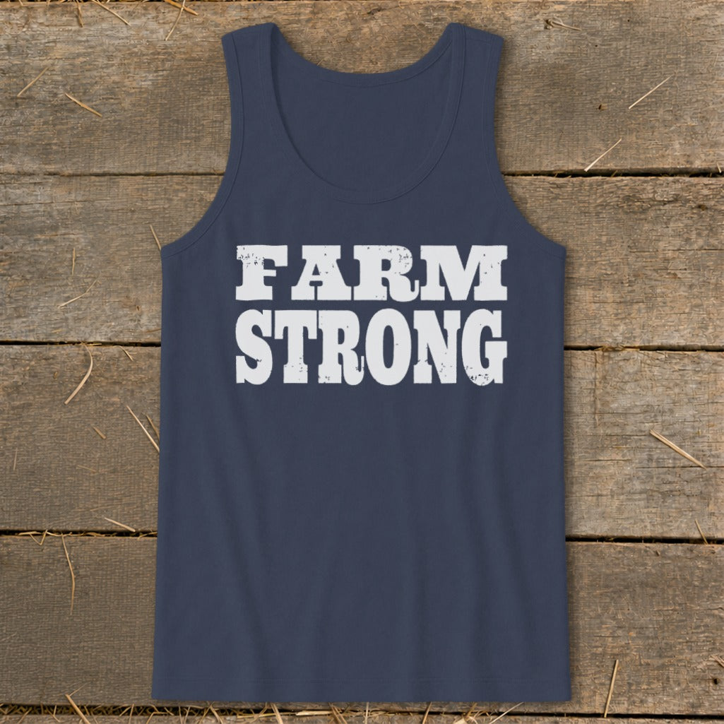 A navy blue tank top featuring the white distressed text FARM STRONG centered on a rustic wooden background.