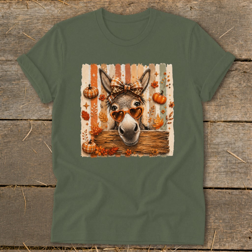 Donkey wearing heart sunglasses and bow, surrounded by autumn leaves and pumpkins.