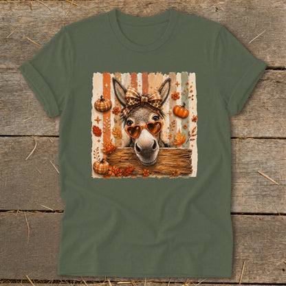 Donkey wearing heart sunglasses and bow, surrounded by autumn leaves and pumpkins.