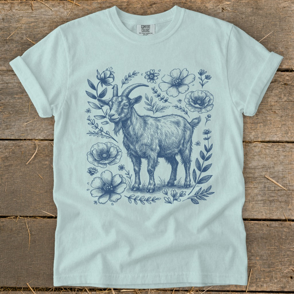 Light blue t-shirt with a sketch of a goat surrounded by blue flowers and foliage.