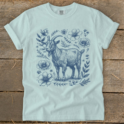 Light blue t-shirt with a sketch of a goat surrounded by blue flowers and foliage.