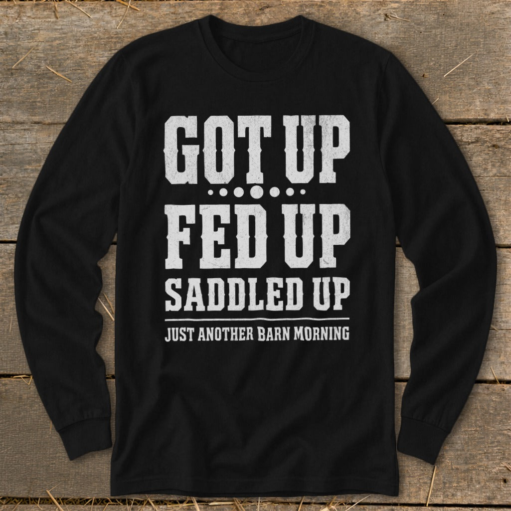 Black long-sleeve shirt with white text "GOT UP FED UP SADDLED UP JUST ANOTHER BARN MORNING."