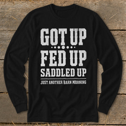 Black long-sleeve shirt with white text "GOT UP FED UP SADDLED UP JUST ANOTHER BARN MORNING."