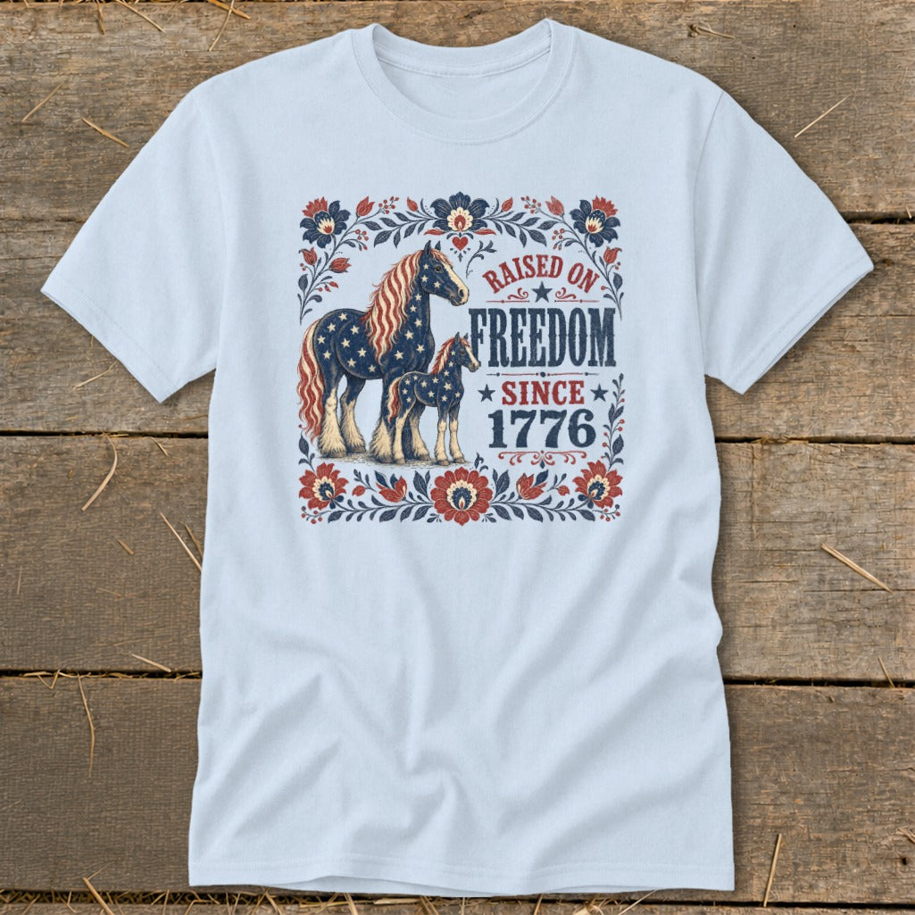 Light blue t-shirt with patriotic horses and "Raised on Freedom Since 1776" text.